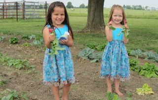 Two of the girls show off their first vegetables of the Spring.
