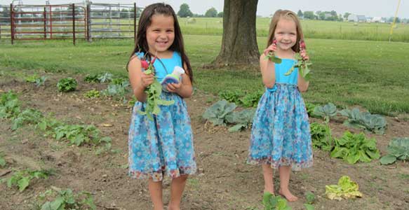 Two of the girls show off their first vegetables of the Spring.